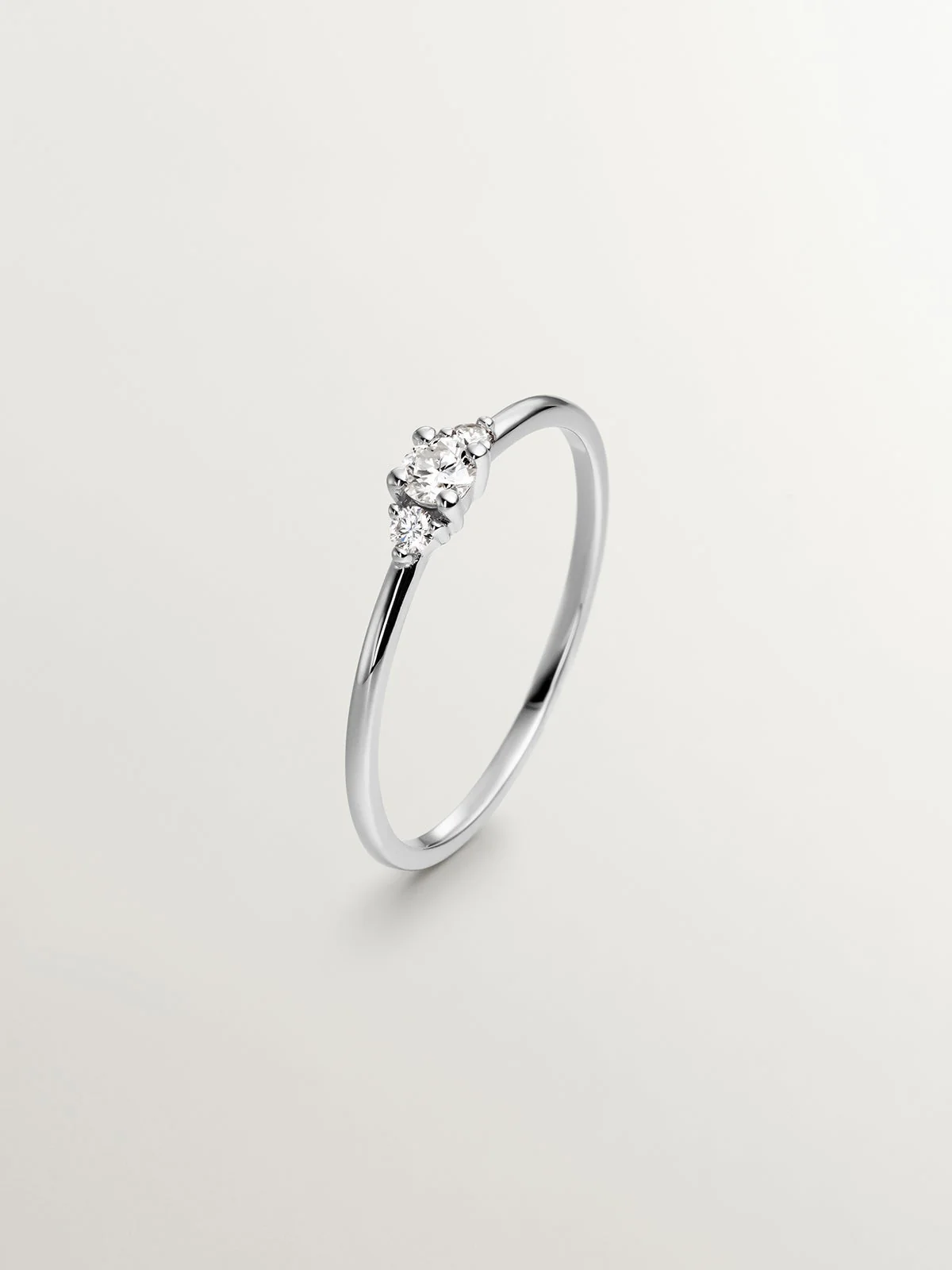 Anillo tresillo de oro blanco de 18K con diamante central de 0,10cts y diamantes