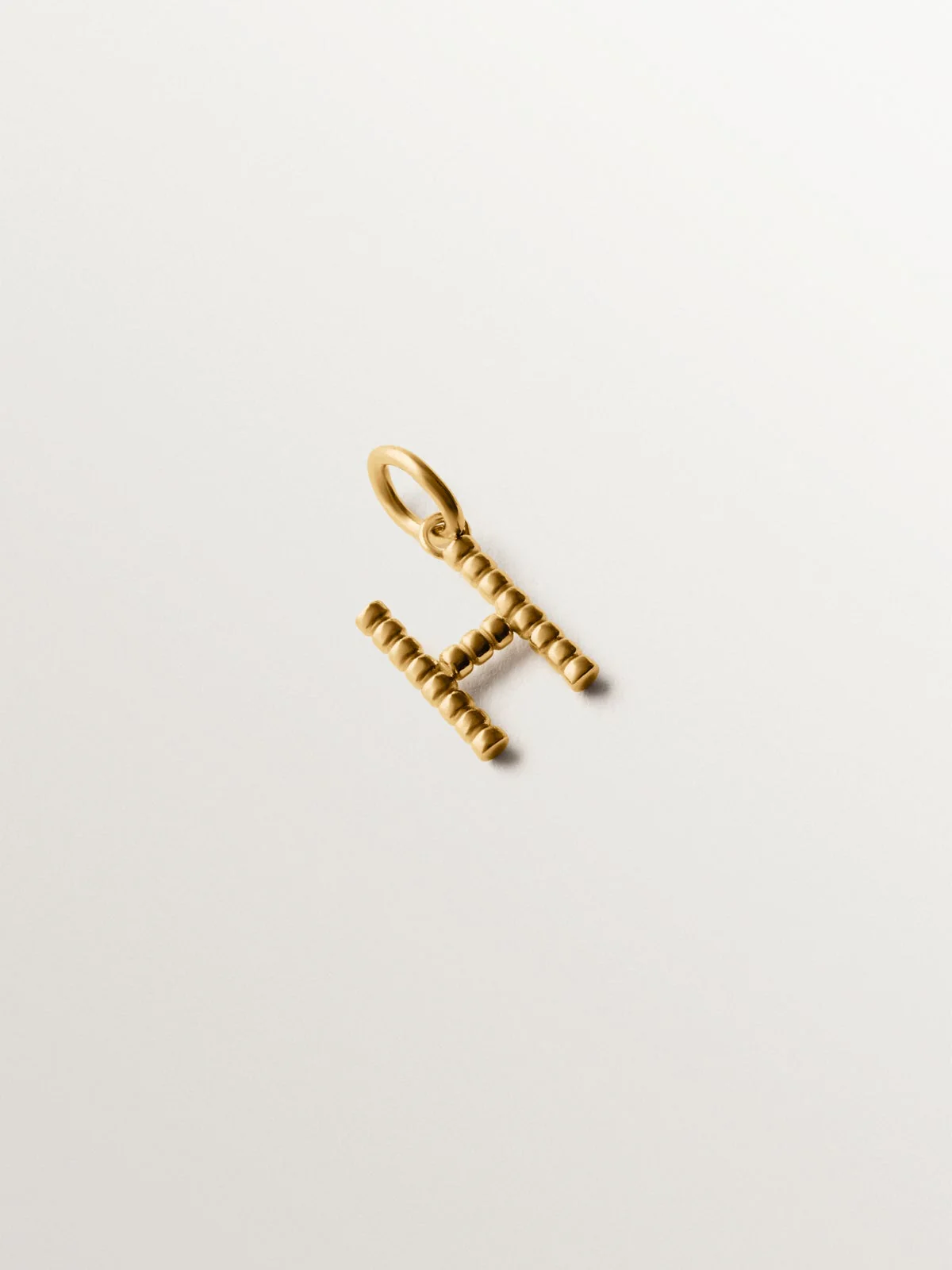 Charm de plata 925 bañada en oro amarillo de 18K con letra H y motivos de esferas