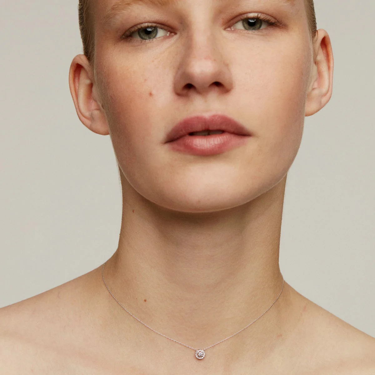 Colgante de oro blanco de 18K con diamante de 0,11cts y orla de diamantes
